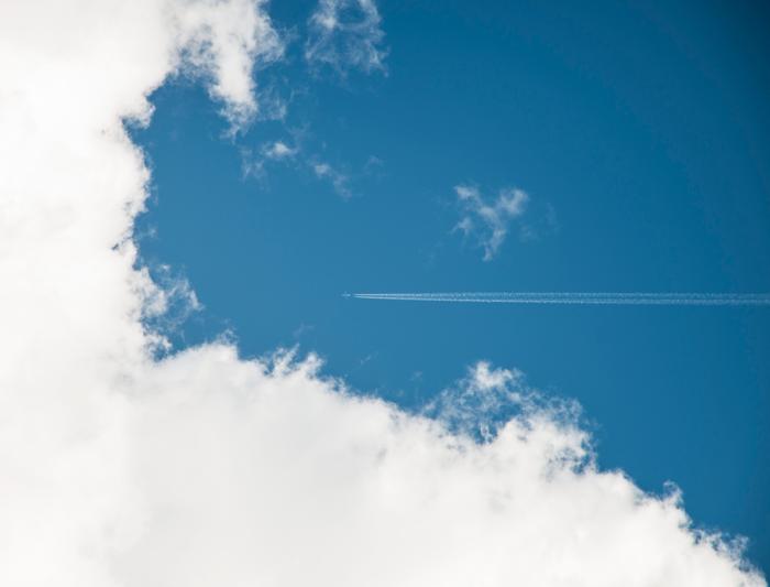 Самолёт с инверсионным следом на фоне голубого неба и белых облаков  — минималистичная художественная фотография неба 